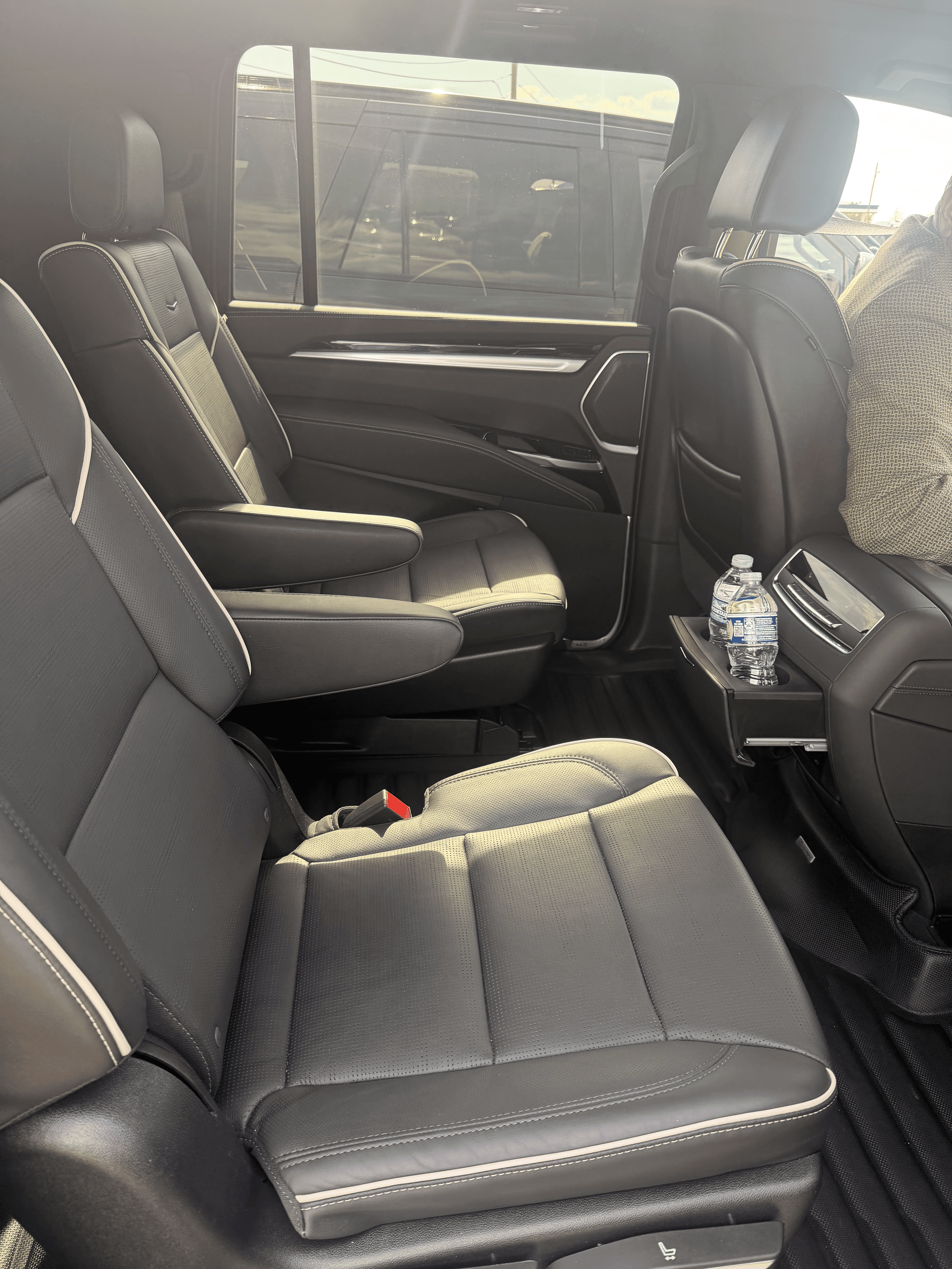 Black leather captain's chairs with white piping inside a luxury vehicle's rear passenger cabin.
